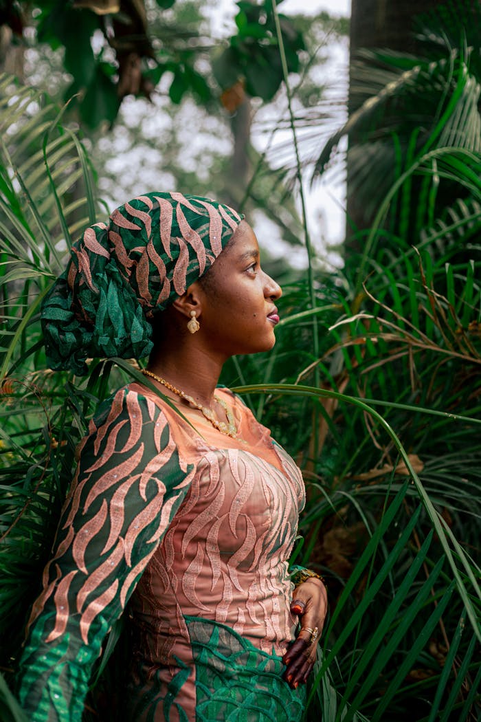 Stylish woman in colorful attire surrounded by lush greenery in an outdoor garden.
